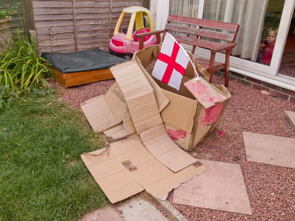 A flag decorates a carboard box house.