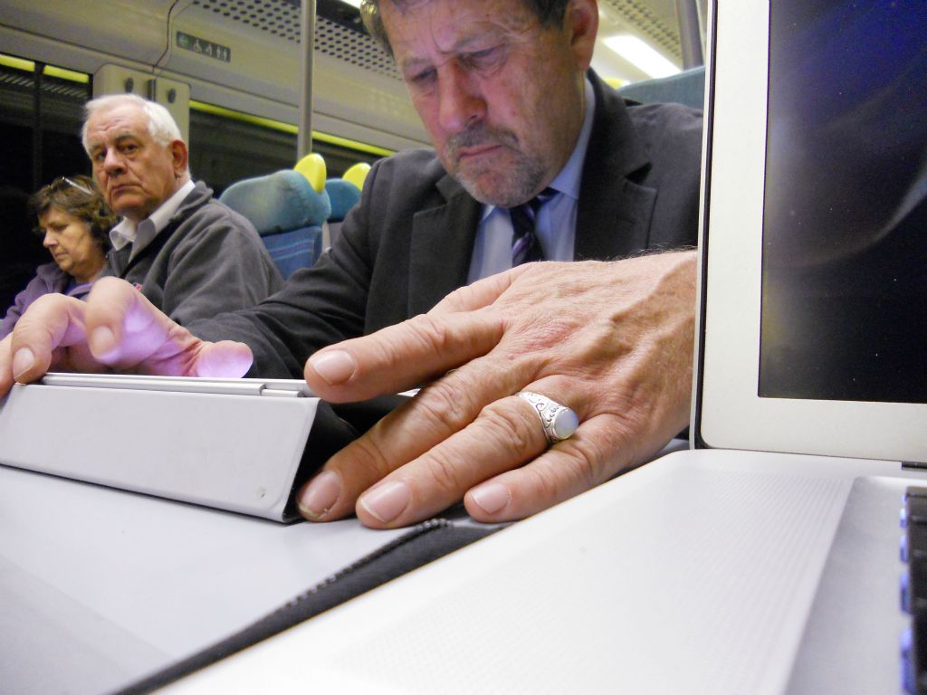 A commuter on an ipad on the train from London to Brighton.