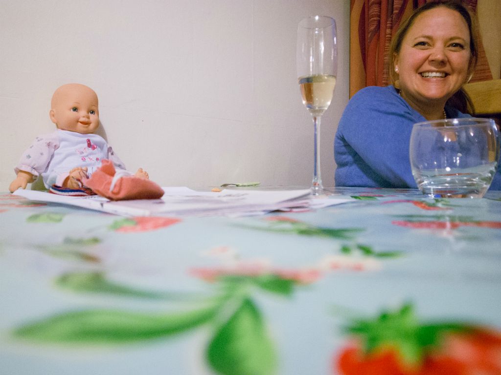 Doll and portrait on table with wine.