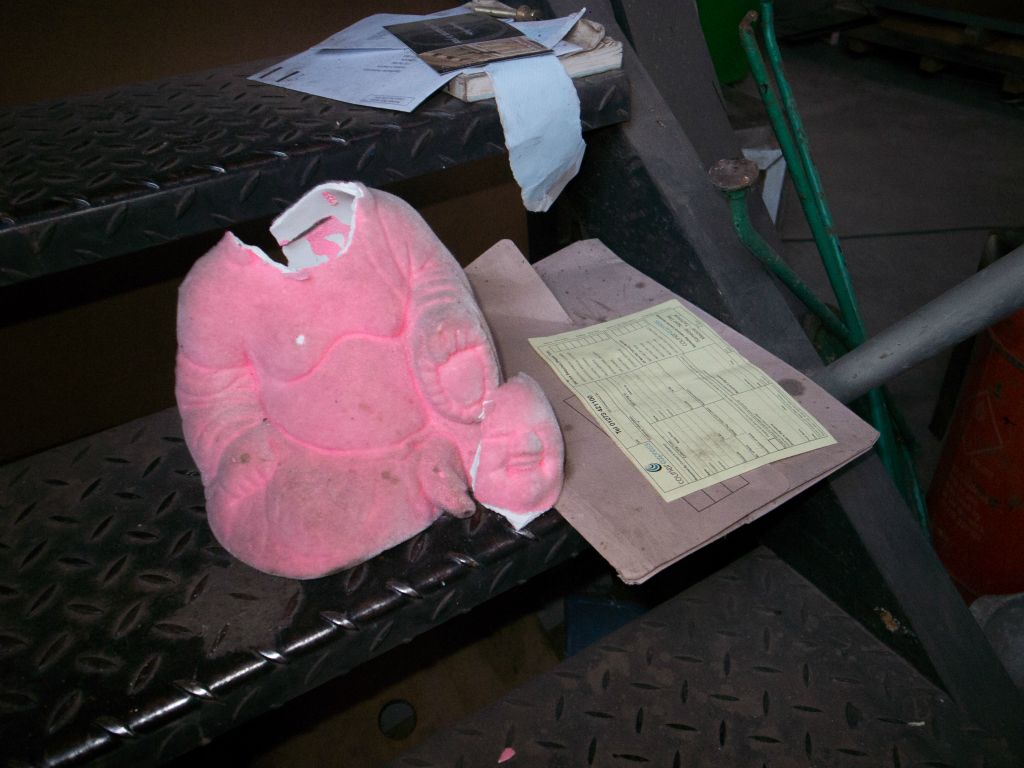 A broken pink Buddha sits by some letters.