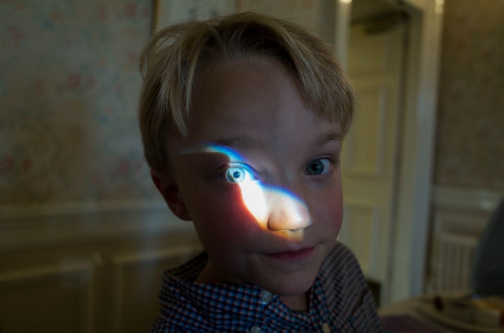 A portrait of a young boy about seven years old with a bright highlight over his right eye.