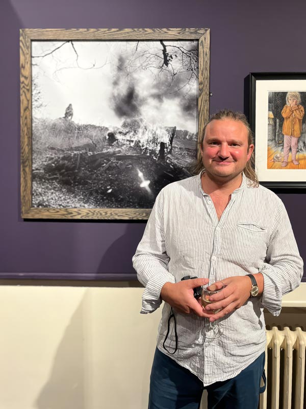 Willie Robb  at the The Hastings Open 2026 next to his print Moving Pyre.